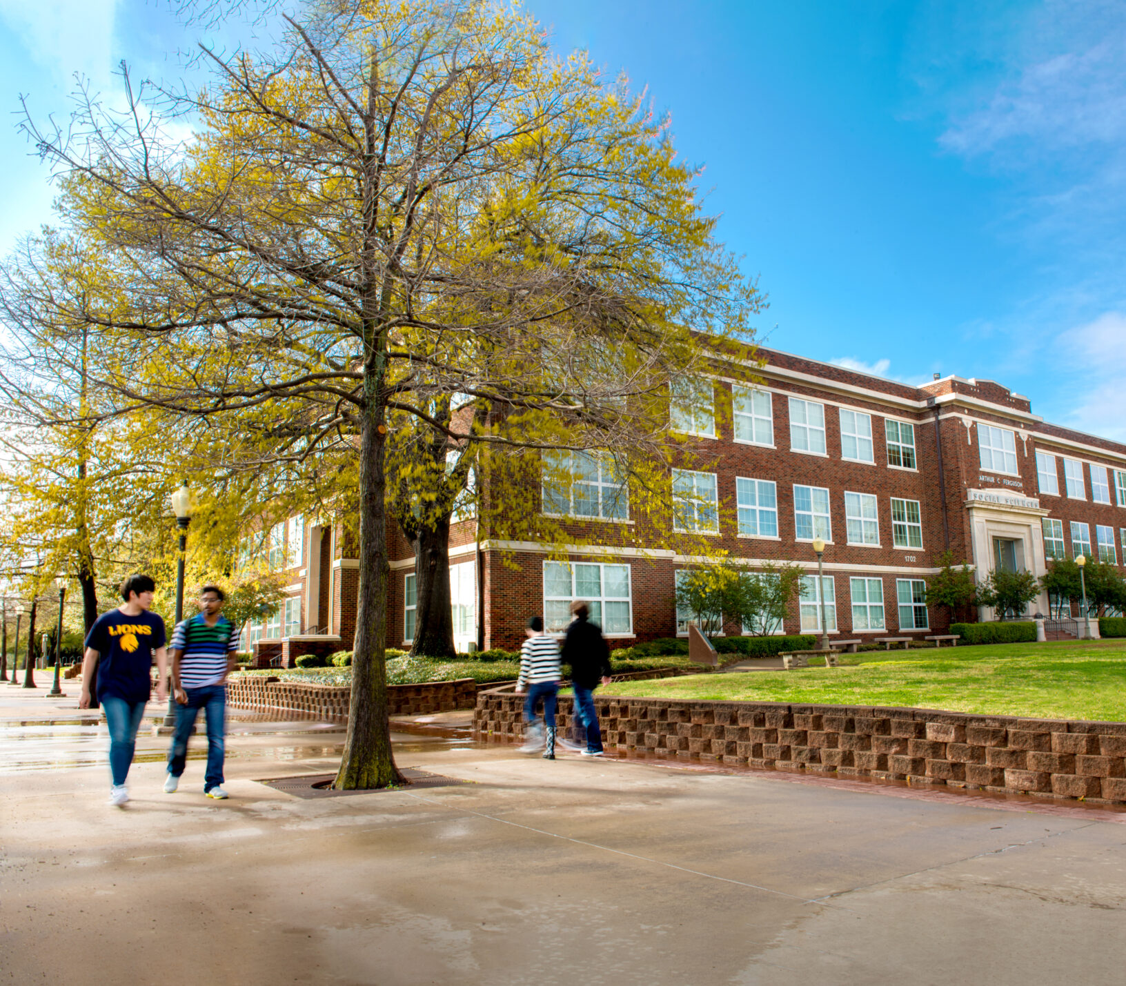 Student walking on campus by the Humanities building.