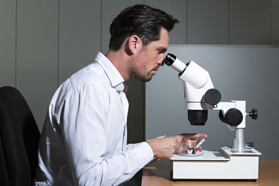 man looking at gem through microscope