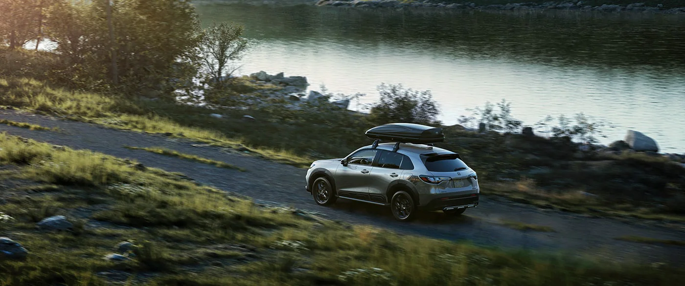 2023 Honda HR-V with storage bin on top driving past body of water.