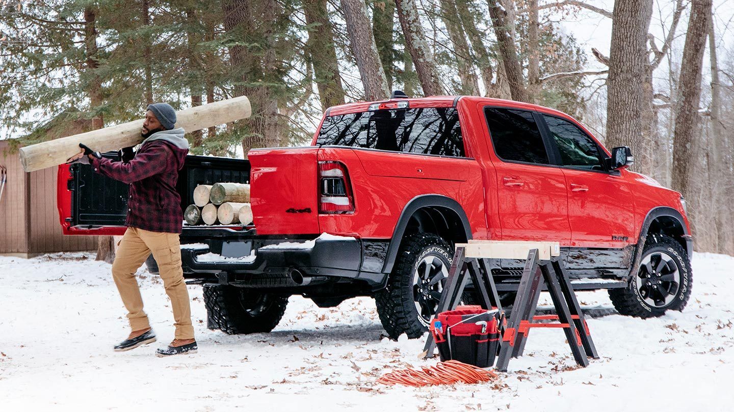 man carrying wood out of his red all-new 2019 ram 1500