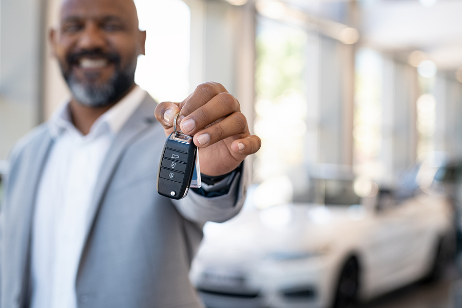 smiling man handing the kays to a new car
