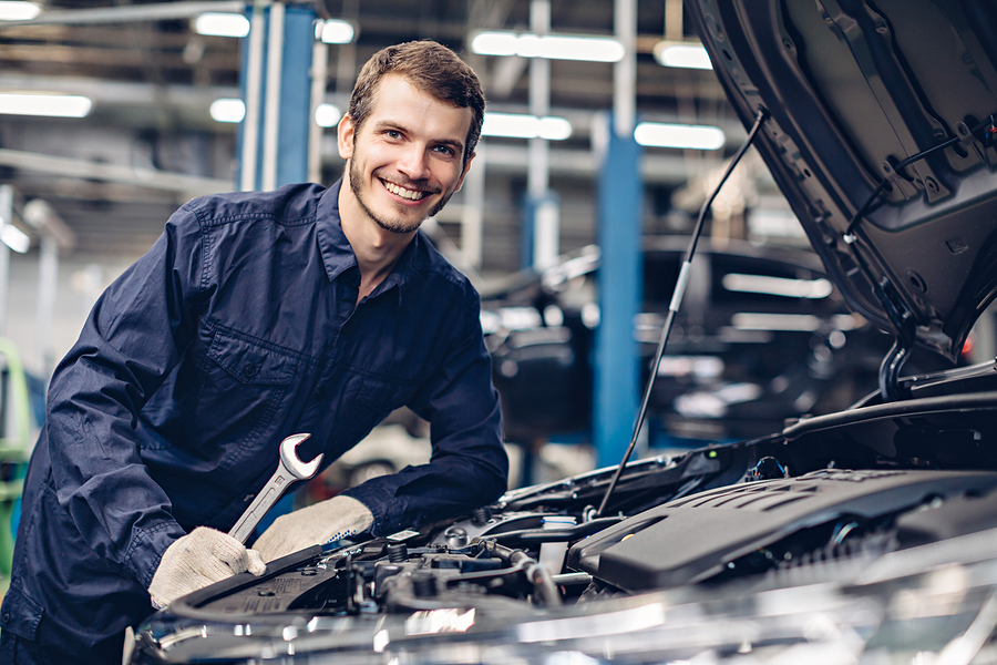 smiling mechanic working in an engine bay