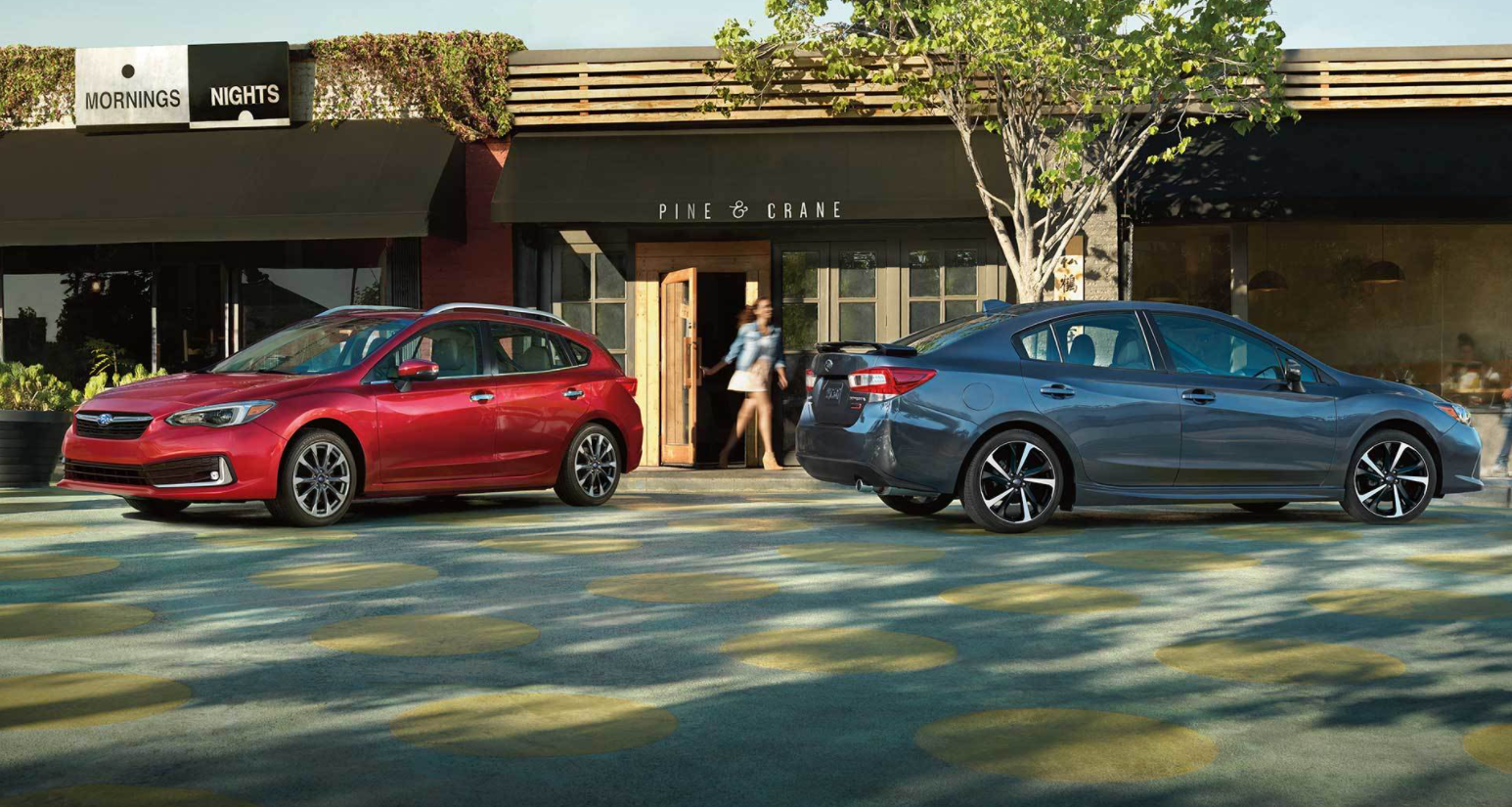 Two 2022 Subaru Legacys, one sedan and one hatchback, parked outside of a business