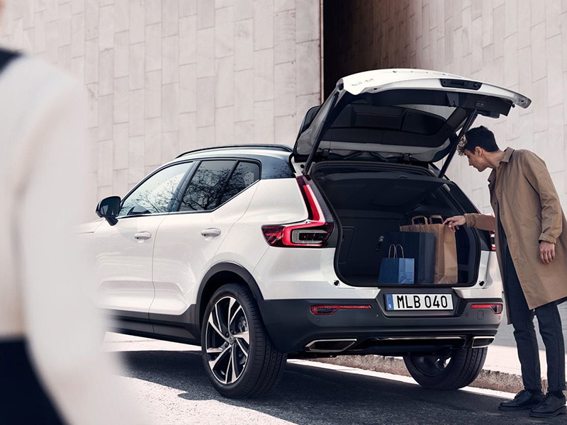 man putting bags into the back of a volvo