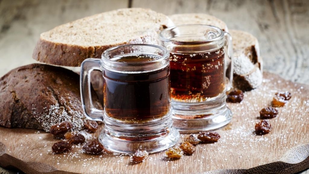 a couple of glasses with brown liquid on a wooden surface