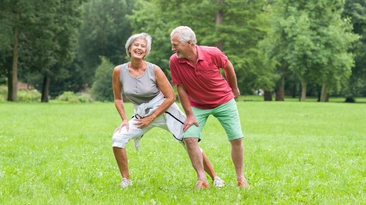 An older couple laugh as they work out in the nature