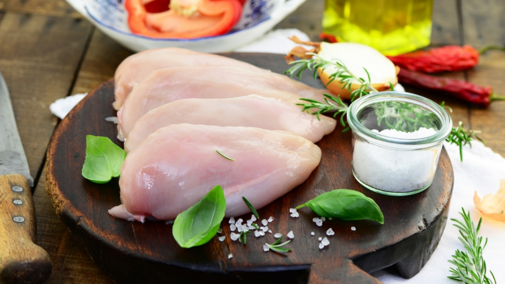 Raw chicken breasts with salt, ready to be cooked