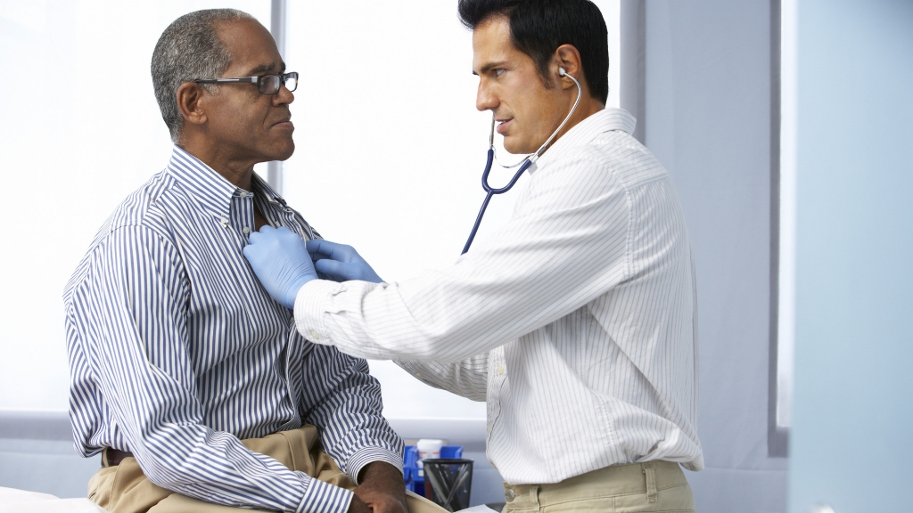 A doctor listening to a man's heart