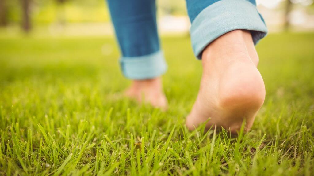 Close'up feet of a woman walking on the grass