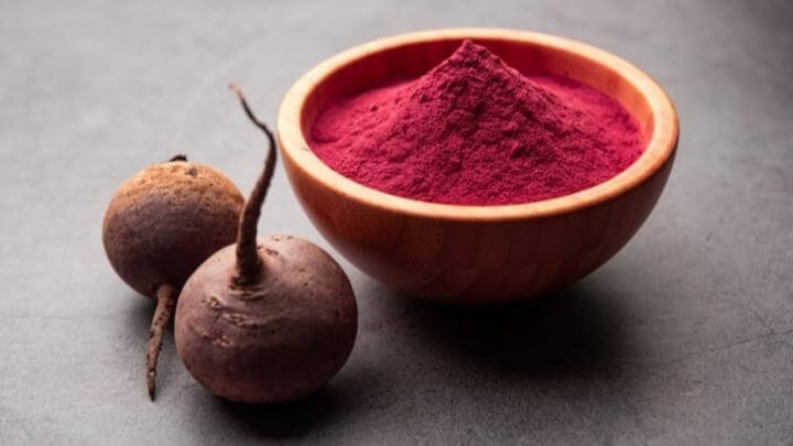 Beetroot powder in a wooden bowl with fresh beetroots