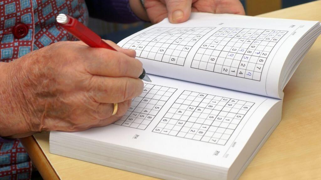 Elderly woman working on sudoku book