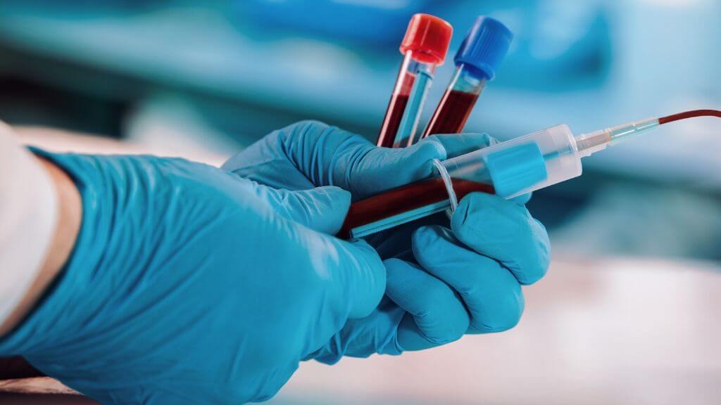 a person in a blue lab coat holding a syringe