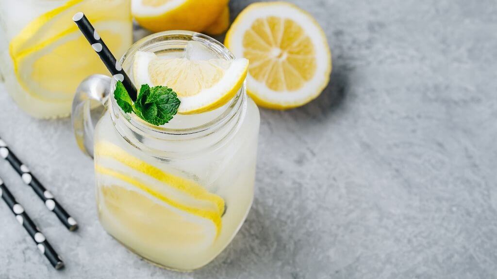 a glass of lemonade with a lemon slice and a lemon slice