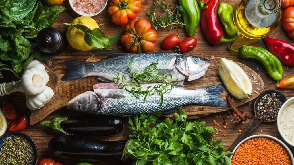 a fish on a table with vegetables