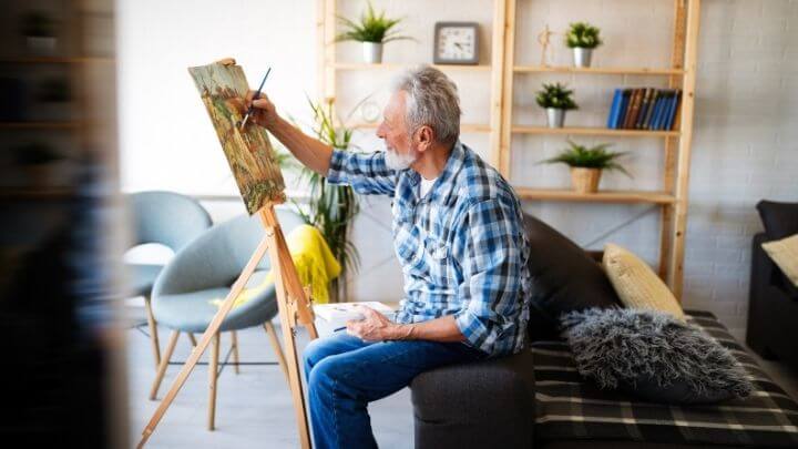 A healthy older man painting at home