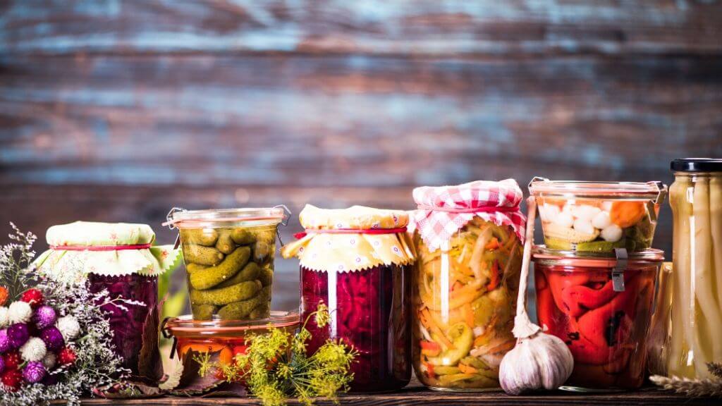 Pickled vegetables in glass jars covered with cloth
