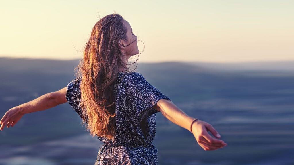 a person with long hair standing in front of water