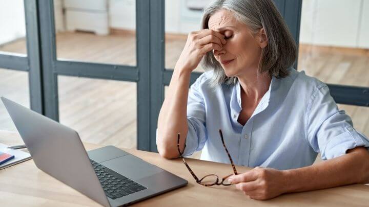 a woman sitting at a table with a laptop and a pen