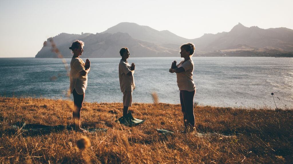 a group of people standing on a grassy hill by a body of water