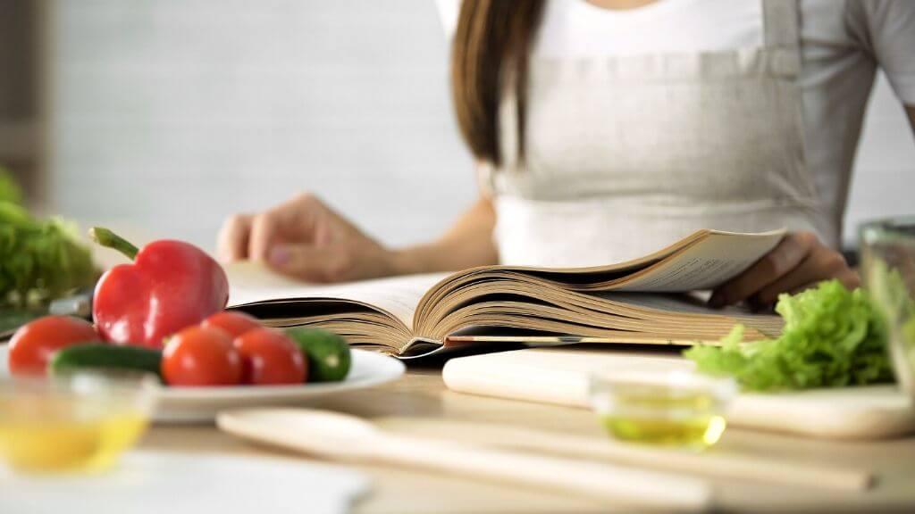 Woman cooking using a cook book