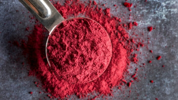 Multivitamin powder in a steel scoop