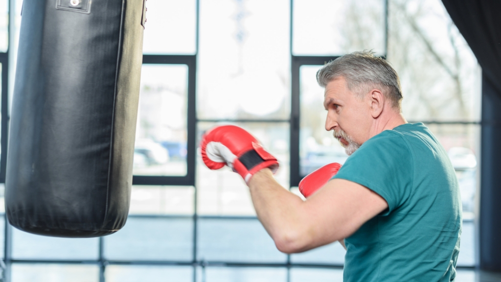 A senior man works out with a punch bag