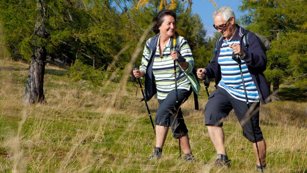 a man and woman walking through a grassy area