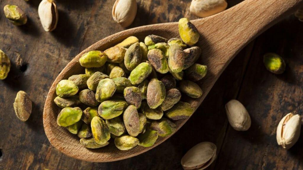 Shelled pistachios in a wooden spoon