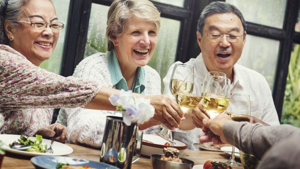 Senior friends raising their glasses at the dinner table