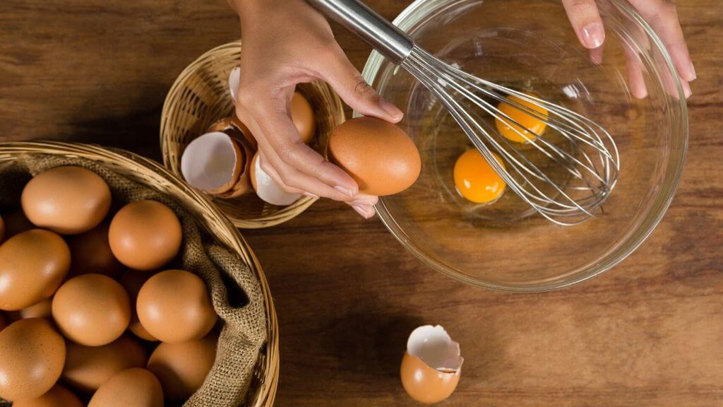 A woman breaking eggs in a large bowl