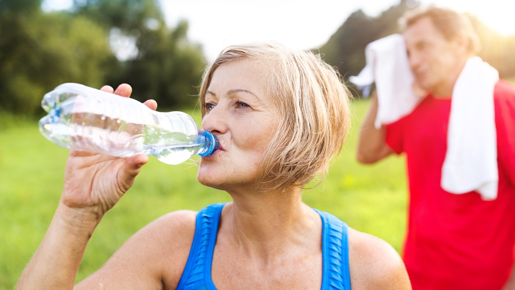 a woman drinking water after outdoor exercise