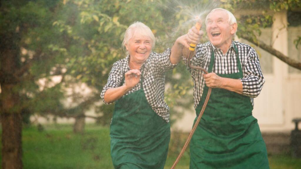 an older couple playing with a water hose