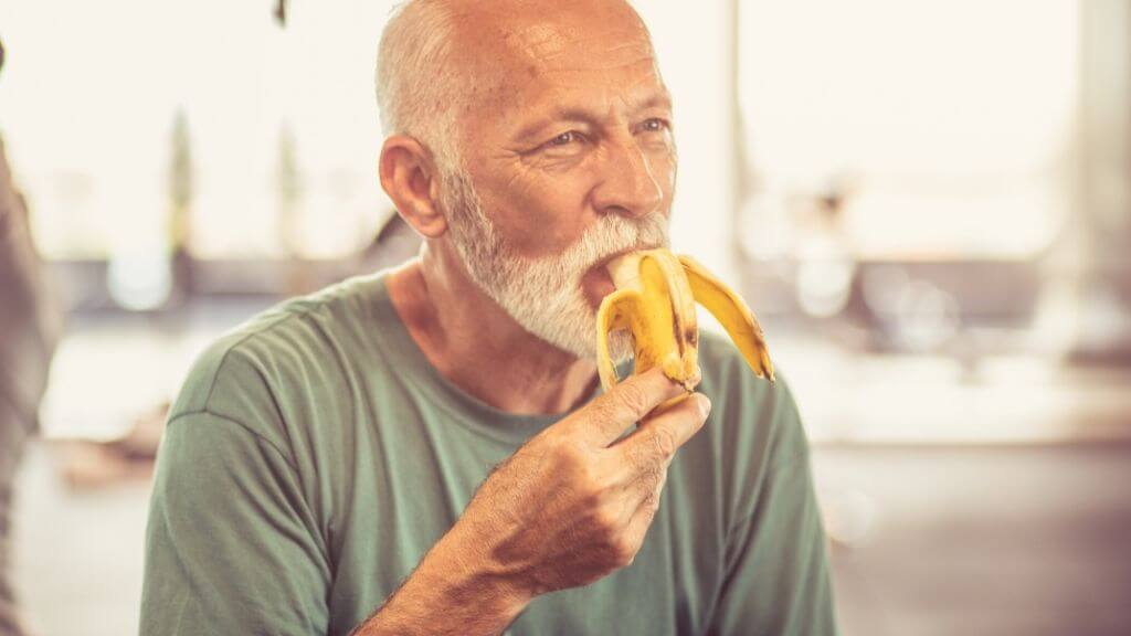 A middle-aged man eating a banana