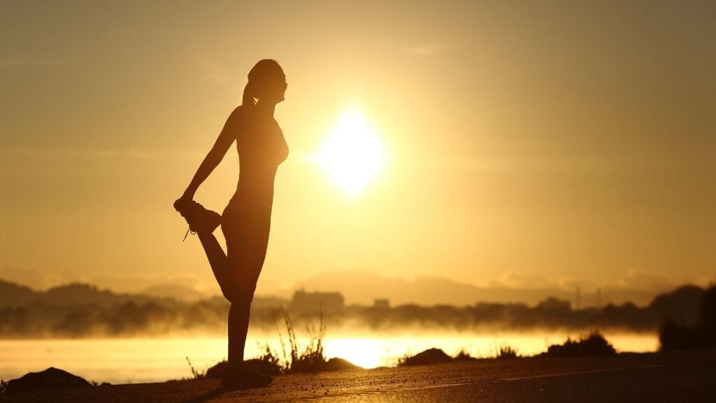 Woman stretching at sunset