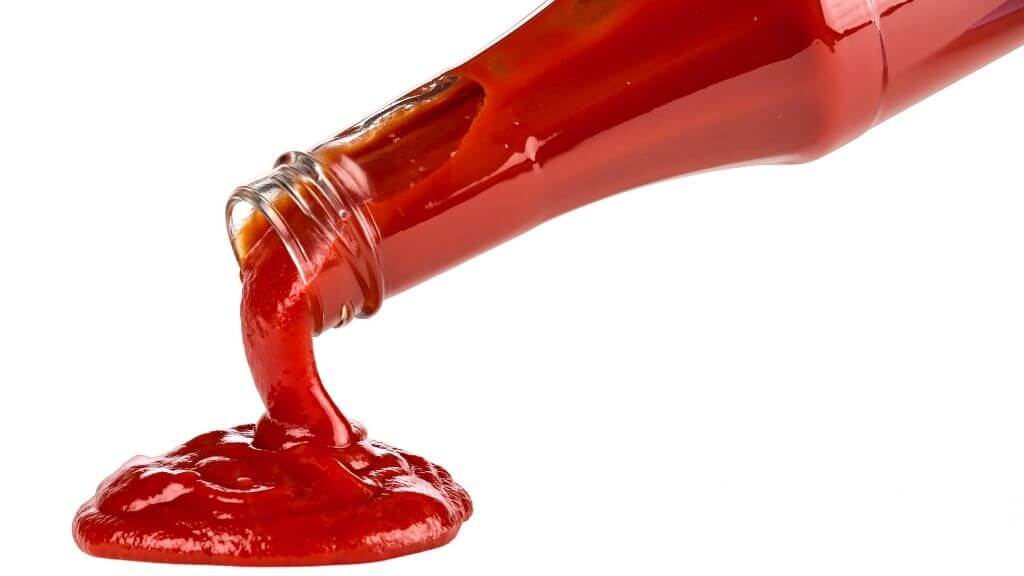 Ketchup bottle pouring ketchup on a white background