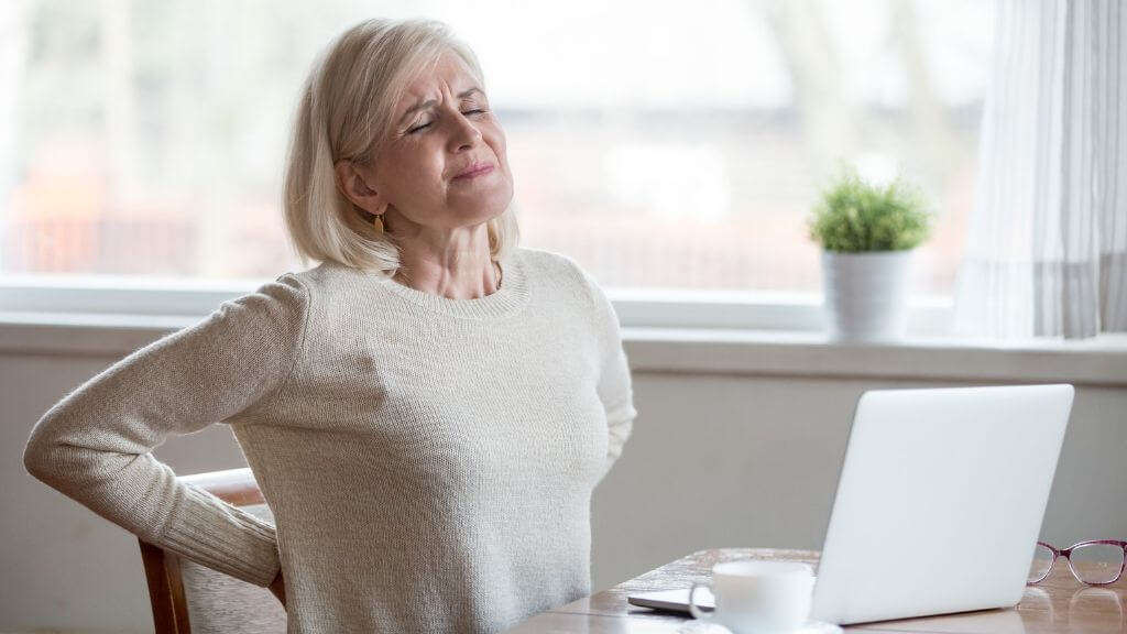 Woman in front of her laptop with back pain