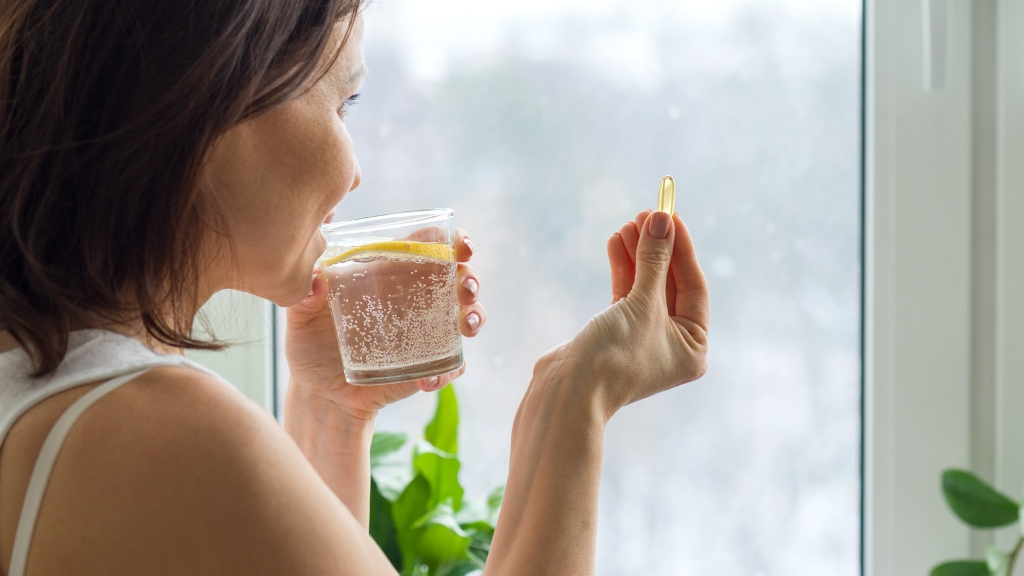 Woman taking a supplement with water with lemon