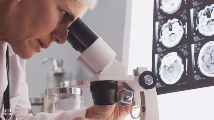 A scientist looking into microscope