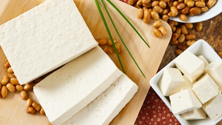 Tofu slices next to soy beans