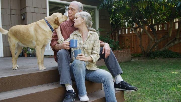 Older couple enjoying a cup of coffee in their front yard with their dog