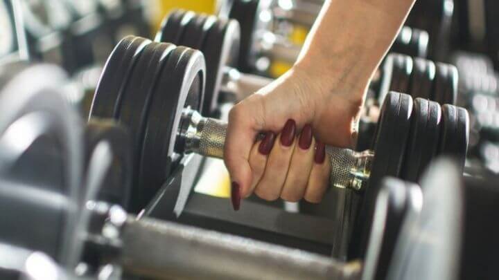 Woman grabbing a dumbbell at the gym 