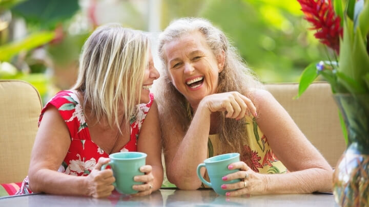 2 older women laughing over coffee