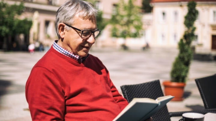 Older man reading a book outside