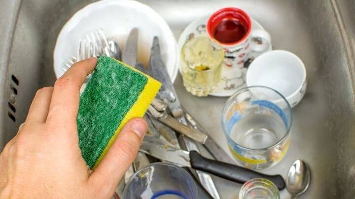 Man holding a sponge, about to do the dishes