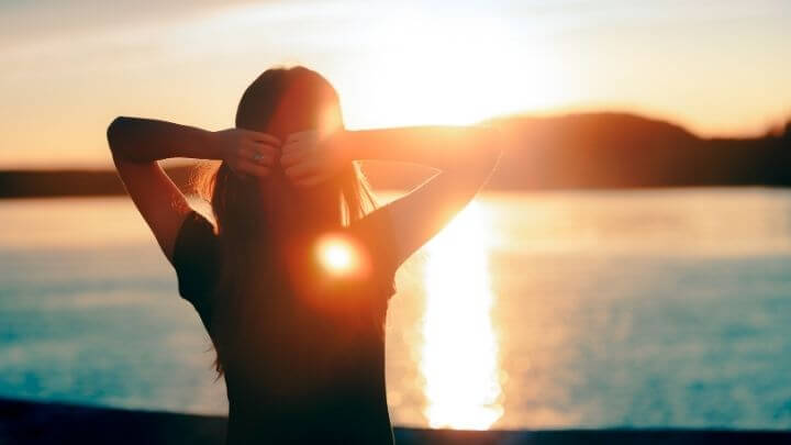 Woman watching the sunset by a lake