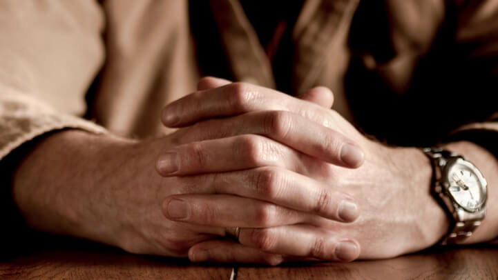 A man's hands with crossed fingers