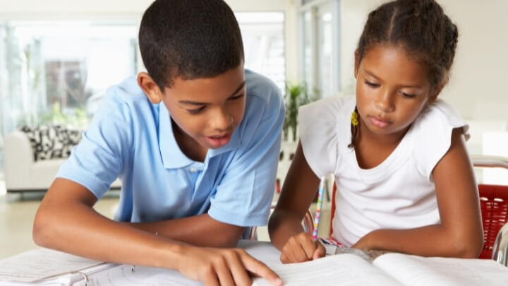 A big brother helping his sister with homework