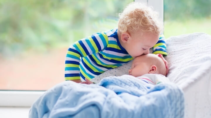 A little kid kissing his baby brother