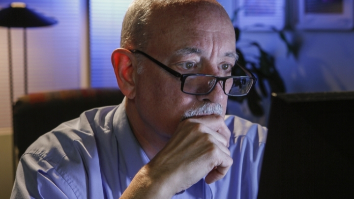 Man with glasses in front of her computer monitor