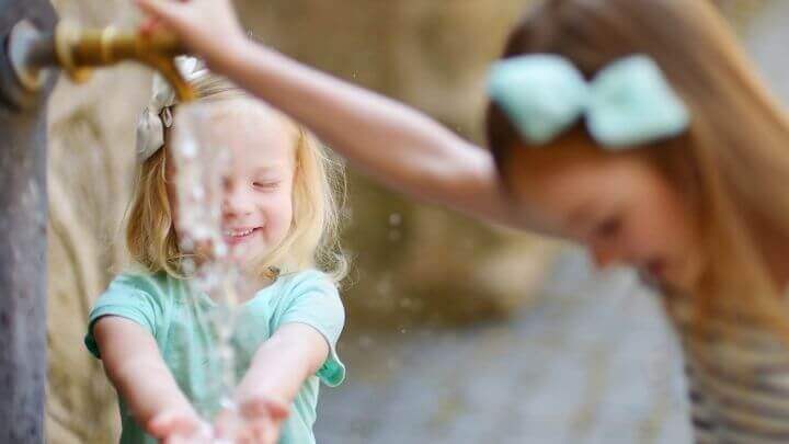 Two little girls playing by a fountain